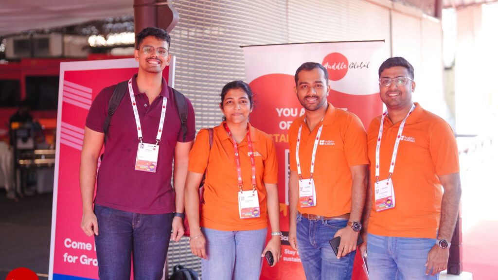 Build to Sustain team members in company polo shirts with a fellow delegate at Huddle Global 2025