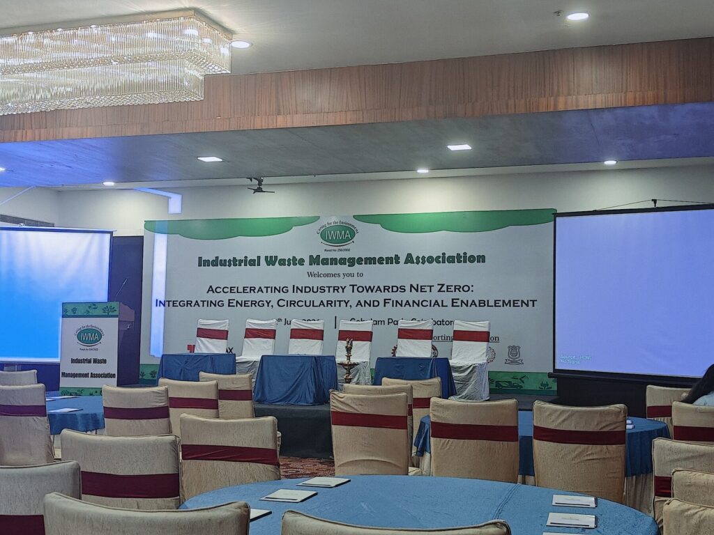 Stage and round tables set up for the Industrial Waste Management Association seminar on accelerating industry towards net zero, Coimbatore